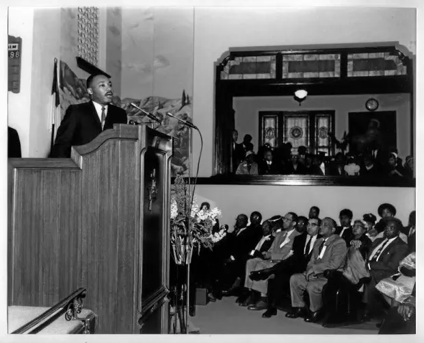 Dr. Martin Luther King speaks to an audience from a podium at the Friendship Baptist Church in Pasadena.